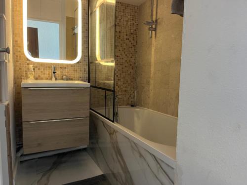 une salle de bain avec un lavabo, une baignoire et un miroir dans l'établissement La Perle de Juan les Pins, à Juan-les-Pins