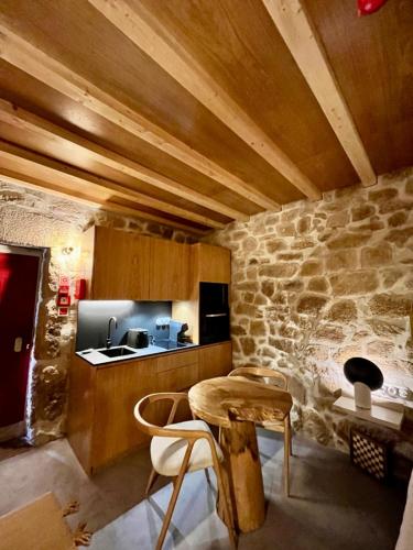a kitchen with a table and a stone wall at Story Studio Sortelha - Heritage in Sortelha