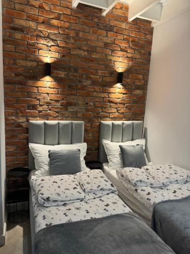 two beds in a room with a brick wall at Borowe Apartamenty in Borowe