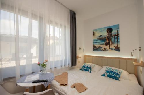 a bedroom with a bed and a table and a window at Családi kikötő apartman in Gyula