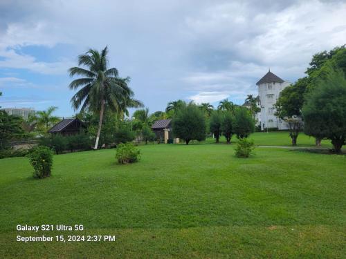 a large green field with a white building in the background at Peaceful Ambiance Awaits at Turtle beach Tower in Ocho Rios