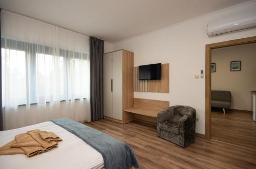 a bedroom with a bed and a chair and a television at Családi kikötő apartman in Gyula