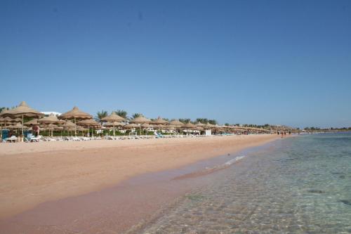 a beach with umbrellas and chairs and the ocean at Gafy Resort Aqua Park in Sharm El Sheikh