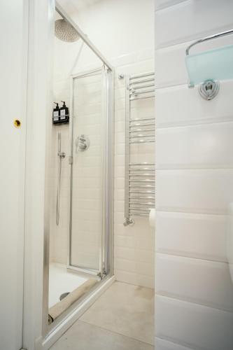 a white bathroom with a shower and a glass door at Casa i Cavalli Alati in Tarquinia
