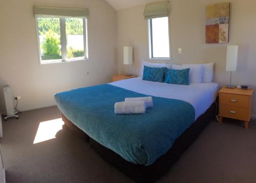 um quarto com uma cama grande e um cobertor azul em Arrowfield Apartments em Arrowtown