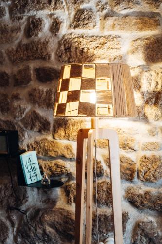 a lamp in a room with a stone wall at Story Studio Sortelha - Heritage in Sortelha