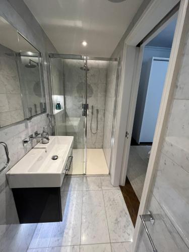 a white bathroom with a shower and a sink at Chelsea flat, convenient and quiet in London