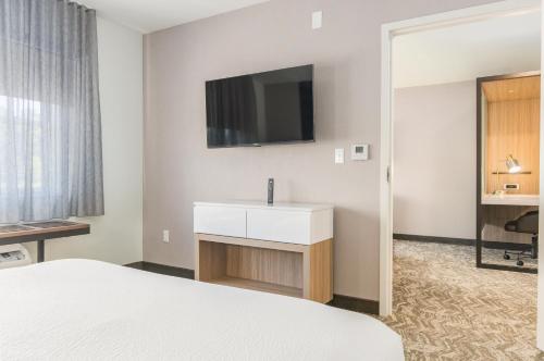 a hotel room with a bed and a tv on the wall at SpringHill Suites by Marriott Freeport Brunswick in Freeport