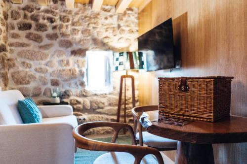 a living room with a couch and a table with a basket at Story Studio Sortelha - Heritage in Sortelha