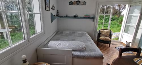 une chambre avec un lit dans une pièce avec des fenêtres dans l'établissement Maison de famille bord de mer, à Ker Pierre Borny