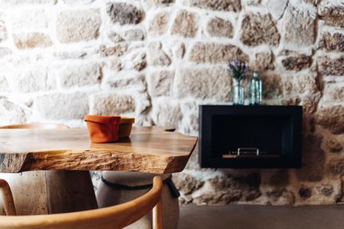 a wooden table with a tv on a stone wall at Story Studio Sortelha - Heritage in Sortelha