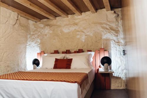 a bedroom with a bed in a stone wall at Story Studio Sortelha - Heritage in Sortelha