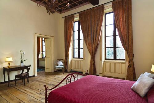 a bedroom with a bed and a desk and windows at Villa Soleil in Colleretto Giacosa