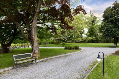 a park with a bench next to a tree at Villa Soleil in Colleretto Giacosa