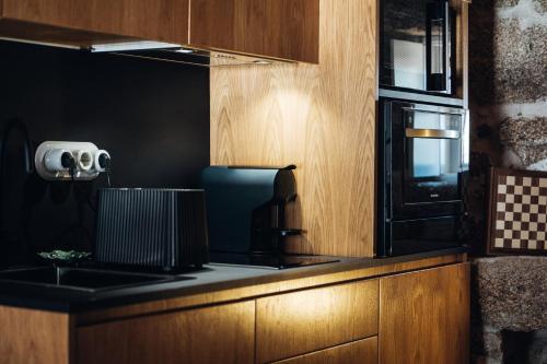 a kitchen with a stove and a microwave at Story Studio Sortelha - Heritage in Sortelha