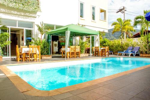 a swimming pool with chairs and a table and a building at Baan Rosa Bangtao Beach in Bang Tao Beach