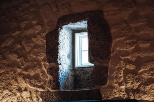 a window in the wall of a stone building at Story Studio Sortelha - Heritage in Sortelha