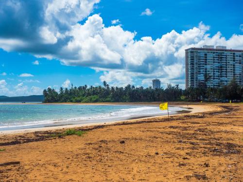 a yellow sign on a beach with a building at Olas Del Mar Beach Apartment in Luquillo