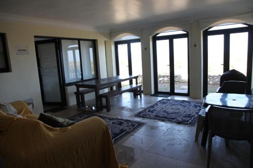 a living room with a table and chairs and windows at Mossel is the Gem of Yzerfontein in Yzerfontein