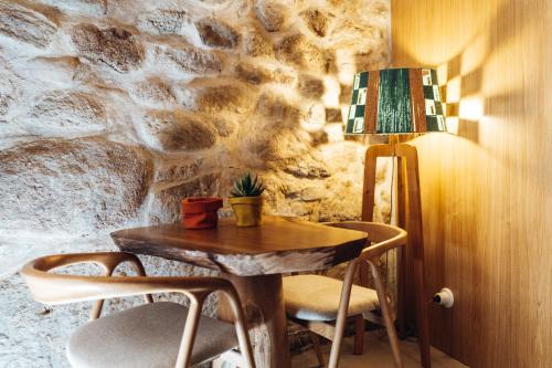 a table and chairs with a lamp and a stone wall at Story Studio Sortelha - Heritage in Sortelha