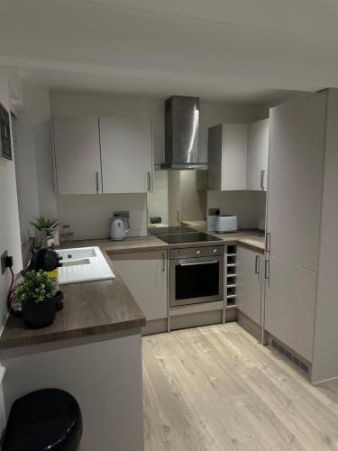 a kitchen with white cabinets and a stove top oven at The Snug - Town Centre Apartment in Bishops Stortford