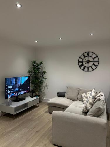 a living room with a couch and a flat screen tv at The Snug - Town Centre Apartment in Bishops Stortford