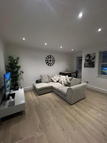 a living room with a couch and a clock on the wall at The Snug - Town Centre Apartment in Bishops Stortford