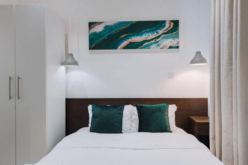 une chambre avec un lit avec des draps blancs et des oreillers verts dans l'établissement Luxury Studio at Embassy Gardens- Prime Location and Convenient, à Accra