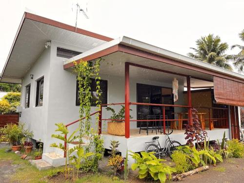 a small white house with a bike in front of it at Tehei Beach House Wifi AC Beachfront Sunset in Punaauia