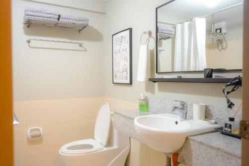 a bathroom with a sink and a toilet and a mirror at Alea Residences in Manila