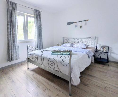 a white bedroom with a bed and a window at Apartment Sea Garden in Ičići