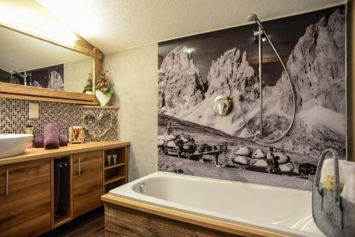 a bathroom with a tub and a painting of mountains at Apartments Haus am Anger - Romantik-Beauty-Wellness in Jungholz