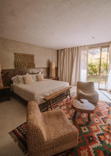 a bedroom with a bed and two chairs and a couch at Zai Patacho in Pôrto de Pedras