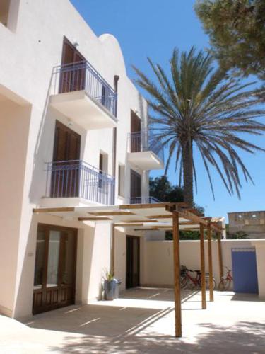 a white building with a palm tree in front of it at Case Vacanza Elisir in Favignana