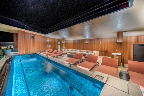 a large swimming pool with orange chairs in a hotel room at One Snowmass West 603 by Snowmass Mountain Lodging in Snowmass