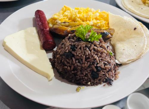 a plate of food with rice and sausage and eggs at Chateau Arenal Hotel & Restaurante in El Castillo de La Fortuna