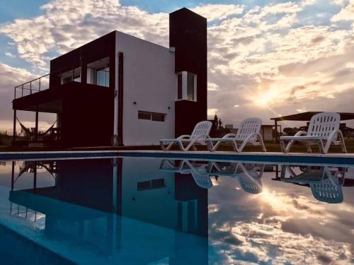 a group of white chairs sitting next to a swimming pool at Casa Puerto del Águila in La Estancia