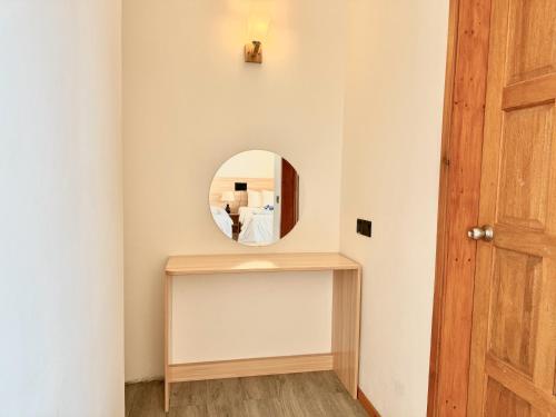 a hallway with a round mirror and a wooden door at La Solara Villa in Ukulhas