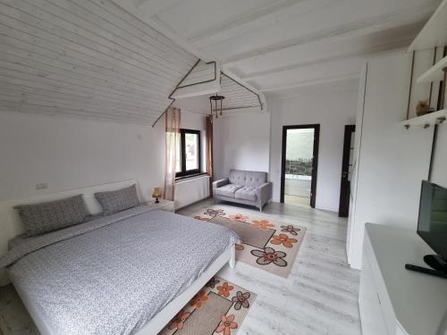 a white bedroom with a bed and a chair at Casa din vale in Bran