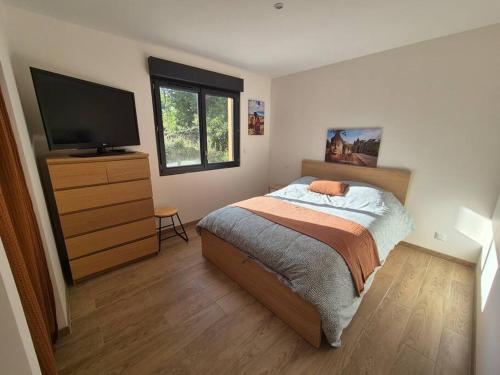 une chambre avec un lit et une télévision à écran plat dans l'établissement Maison au pied du Puy-de-Dôme, à Ceyssat