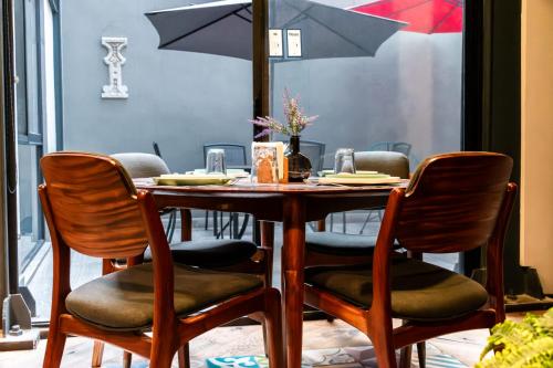 a dining room table with chairs and an umbrella at Lujoso Depto con Espectacular terraza a unos pasos del Angel in Mexico City