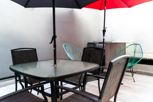 a table and chairs with umbrellas in a room at Lujoso Depto con Espectacular terraza a unos pasos del Angel in Mexico City