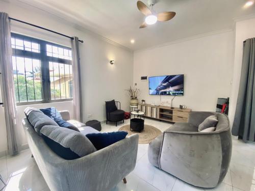 a living room with two couches and a flat screen tv at Sunset Views 3-Bedroom Apt, 1min Walk to Beach - NYHA1 in Flic-en-Flac