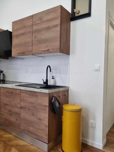 a kitchen with wooden cabinets and a yellow trash can at Le Vauban Cambrai in Cambrai