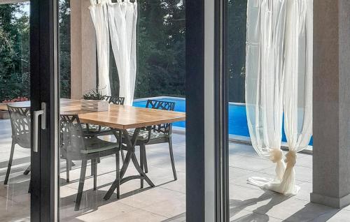 a wooden table and chairs on a patio with curtains at Lovely Home In Lovrin in Heki