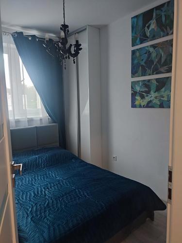 a bedroom with a blue bed and a window at Apartament LUX w centrum Konina in Konin