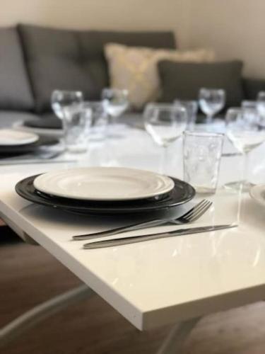 - une table blanche avec des assiettes et des verres dans l'établissement Authentique House à côté de Disneyland Paris, à Montévrain