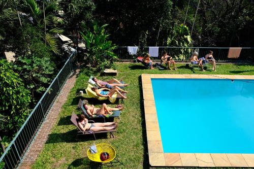 a group of people laying on lawn chairs next to a swimming pool at Castelo dos Tucanos Host in Rio de Janeiro