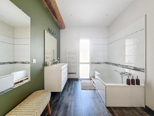 a bathroom with white cabinets and a sink and a tub at Le Clos Fleuri in Châtillon-sur-Chalaronne