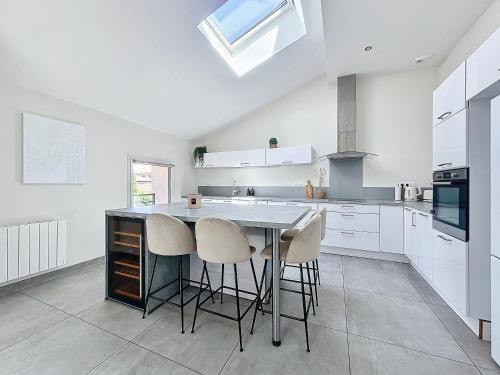 une cuisine avec des armoires blanches et une table avec des tabourets dans l'établissement Le Clos Fleuri, à Châtillon-sur-Chalaronne